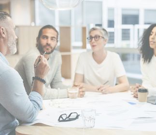 ASSMANN HOME Unternehmensprogramm Vier Personen sitzen an einem Tisch im modernen Büro.