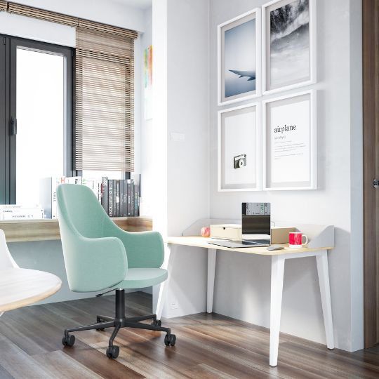 Moderner Arbeitsplatz mit grünem Bürostuhl, hellem Holztisch und Bildern an der Wand.