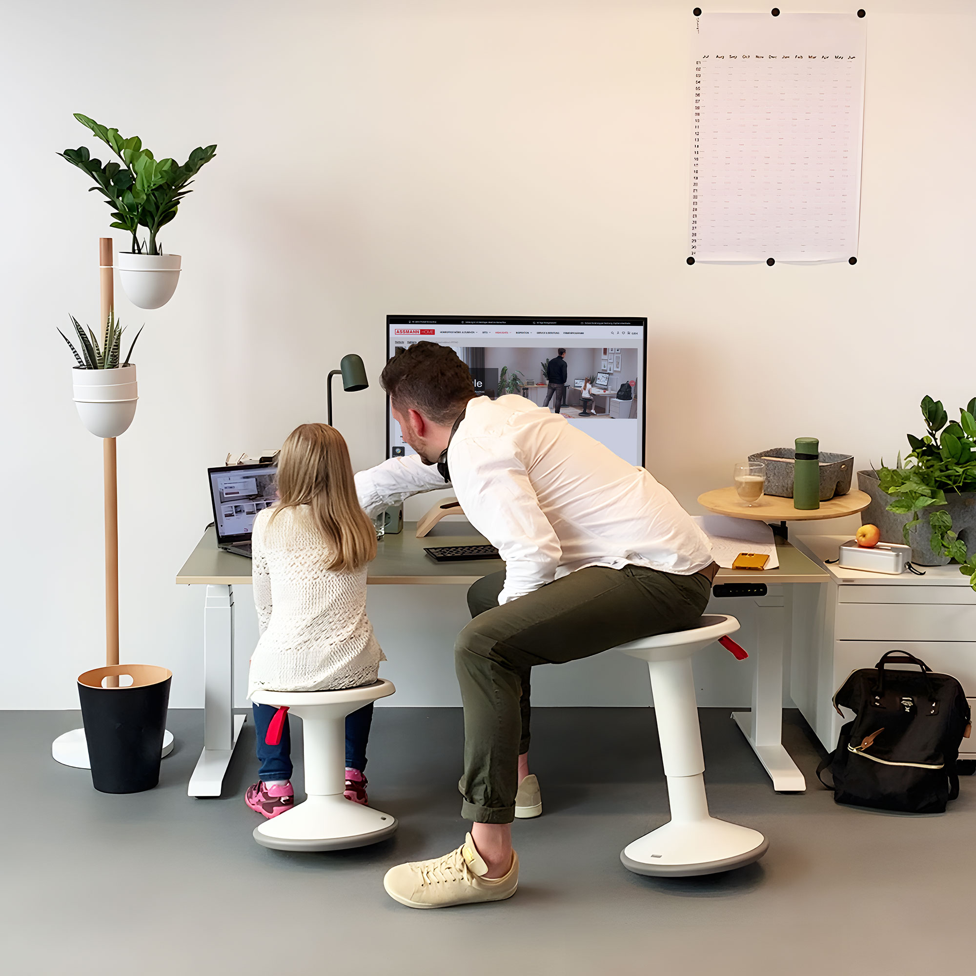 Modernes Homeoffice mit Vater und Tochter an einem Schreibtisch, umgeben von Pflanzen.