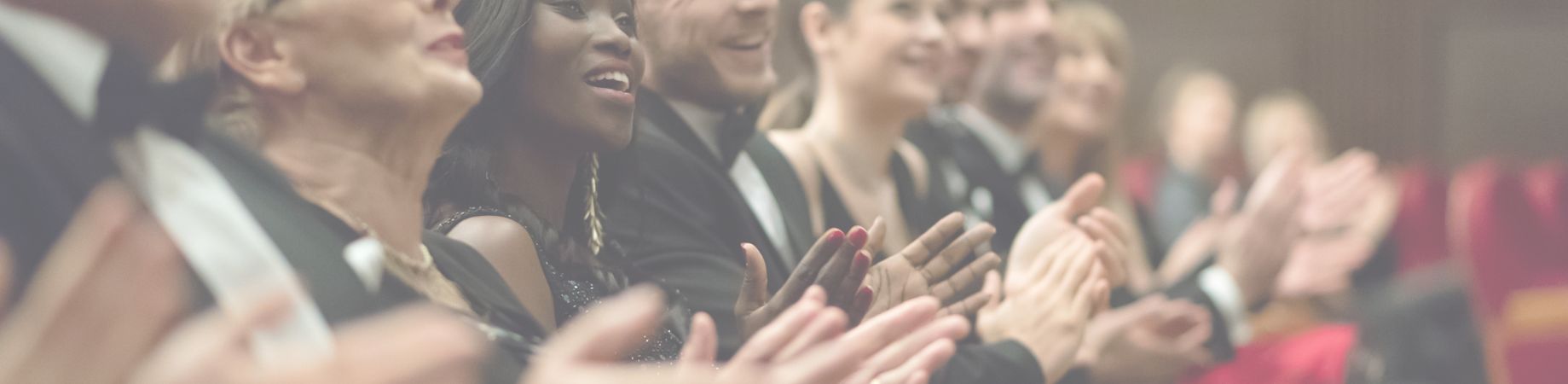 Eine Gruppe von applaudierenden Menschen in formeller Kleidung.
