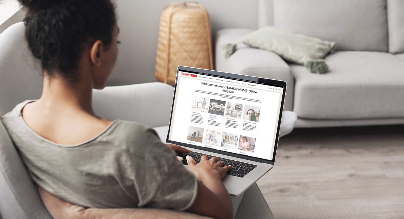 Eine Person sitzt auf einem Sofa und betrachtet eine Website auf einem Laptop. Die Seite zeigt Inhalte zum Thema Home-Office.