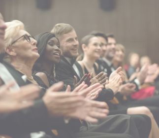 World Design Day Eine Gruppe von Menschen, die applaudieren, während sie auf Stühlen sitzen.