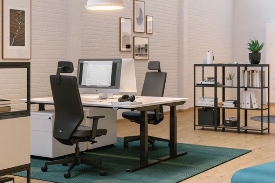 Ein modernes Büro mit zwei Schreibtischen, Bürostühlen, einem Computer, Regalen und dekorativen Elementen.