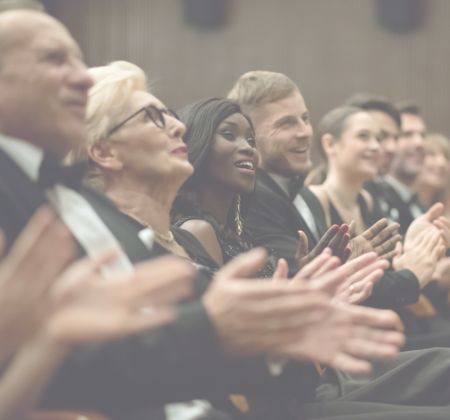 Eine Gruppe von Menschen in formeller Kleidung applaudiert.