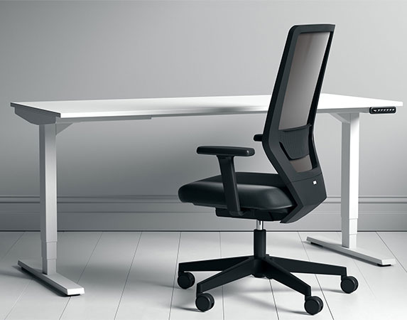 Ergonomischer Bürostuhl mit Netzrückenlehne vor weißem Sitz-Steh-Schreibtisch