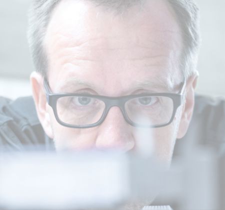 Zertifizierte Ergonomie, Sicherheit & Qualität: Optimiere dein Homeoffice Nahaufnahme eines Mannes mit Brille, der fokussiert auf ein Objekt schaut.