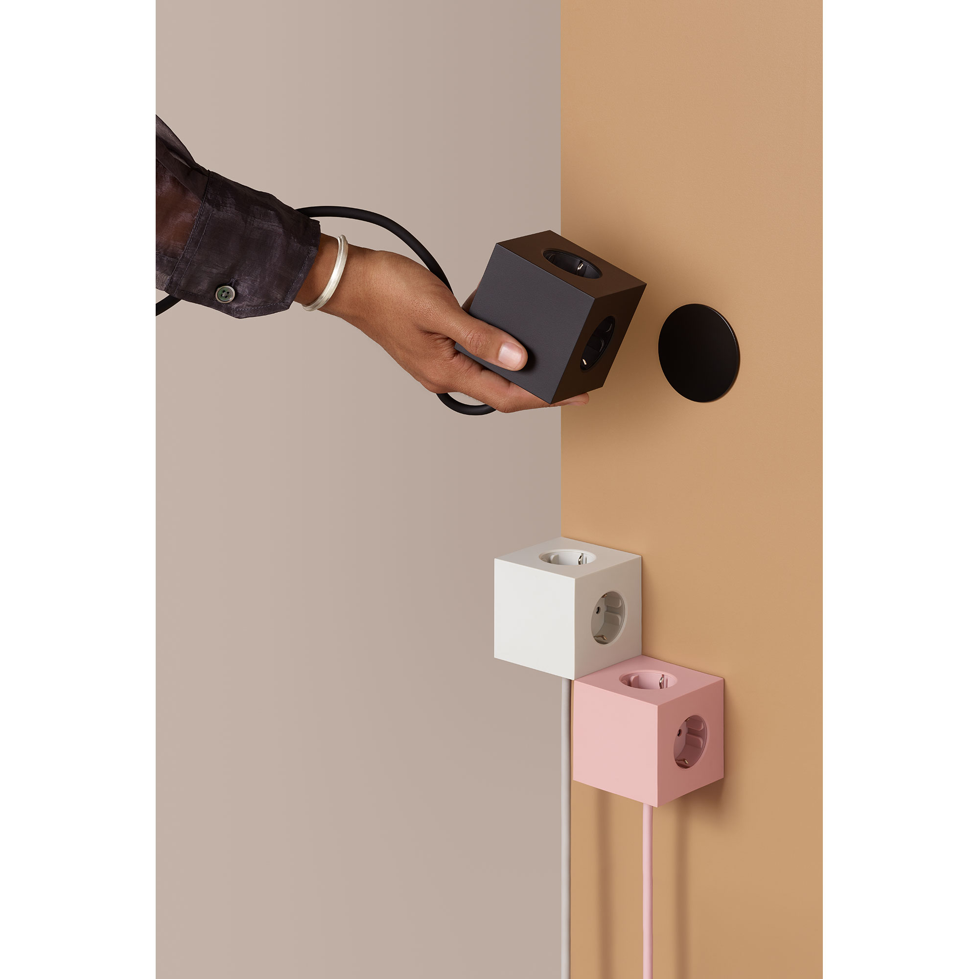 Design-Mehrfachsteckdosen in Schwarz, Weiß und Rosa von AVOLT – stilvoll an der Wand montiert, ideal für modernes Wohnen und Arbeiten