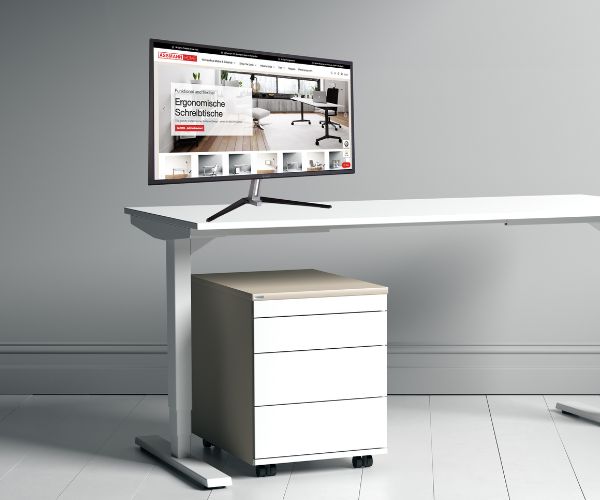 Ein moderner Schreibtisch mit einem Computerbildschirm, der eine Webseite zeigt, und einer rollbaren Schubladeneinheit.