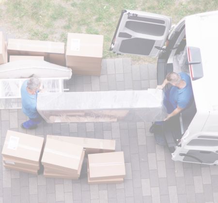 Zwei Männer beim Möbeltransport, tragen große verpackte Ware aus Lieferwagen
