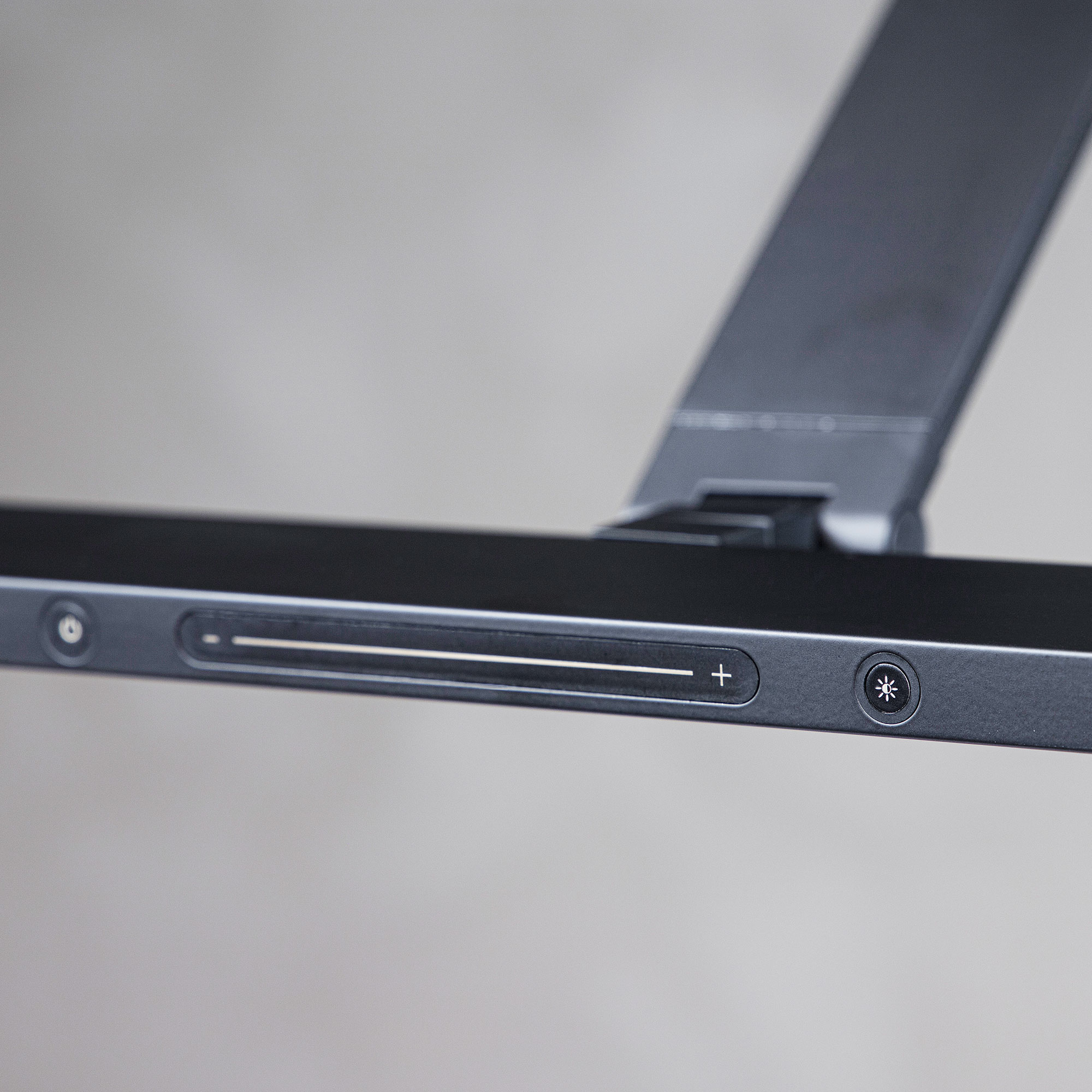 Detailansicht der schwarzen Touch-Bedienleiste einer LED-Schreibtischlampe mit Helligkeitsregelung.