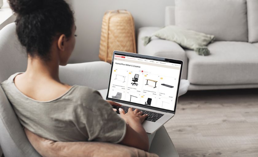 Frau beim Online-Shopping für Homeoffice-Möbel auf dem Sofa mit Laptop