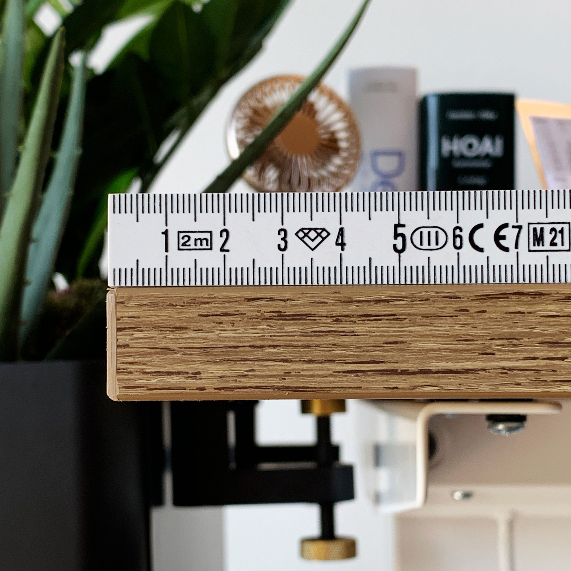 Schreibtischkante aus Holz mit Maßband zur Dickenmessung.